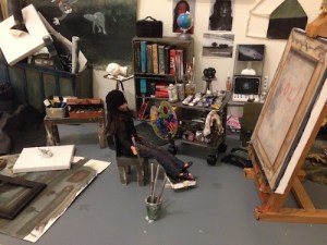 Close-up of the doll-artist contemplating her studio output in Julia San Martin’s Dollhouse