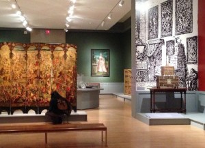 Visitor inspects painted screen in exhibit area with the objects from the grand reception room of an upscale home.
